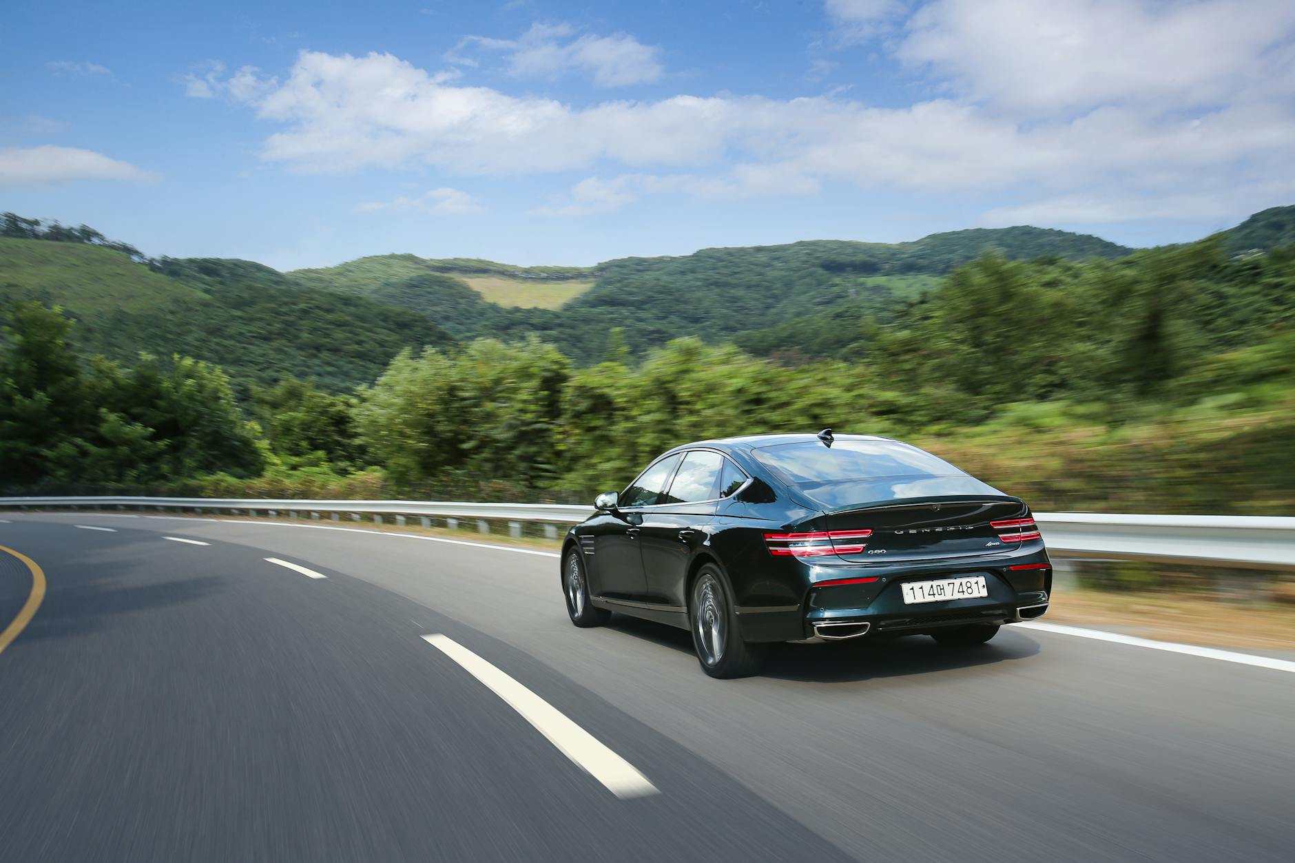 Czarny sedan sportowy jedzie krętą drogą wśród zielonych gór