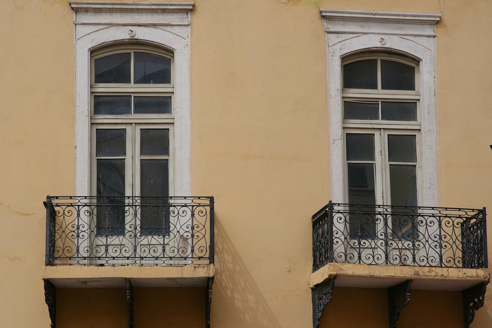 Dwa eleganckie balkony z kutą balustradą na beżowej kamienicy w Izmirze