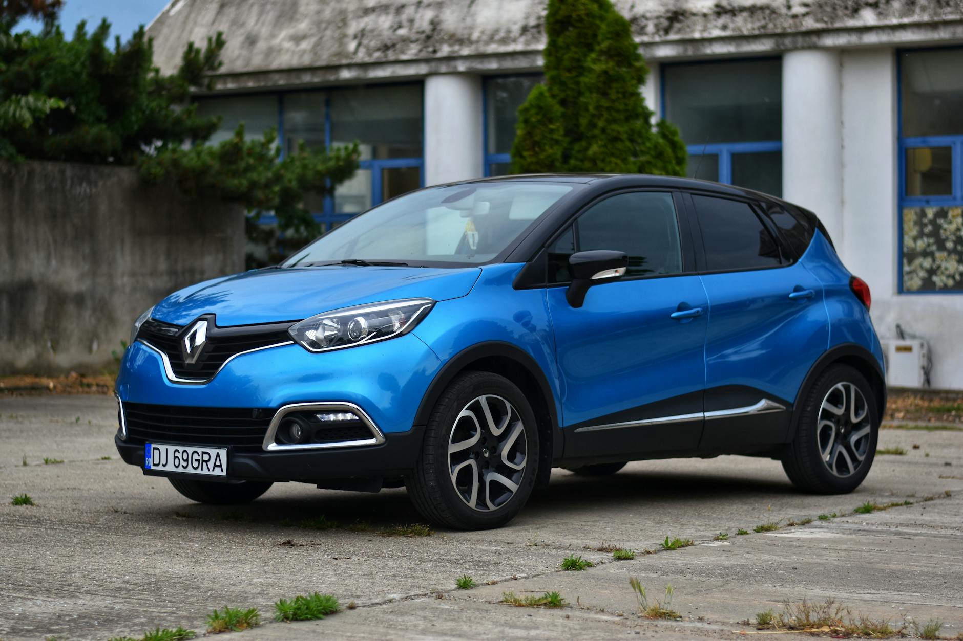 Niebieski Renault Captur zaparkowany przed nowoczesnym budynkiem