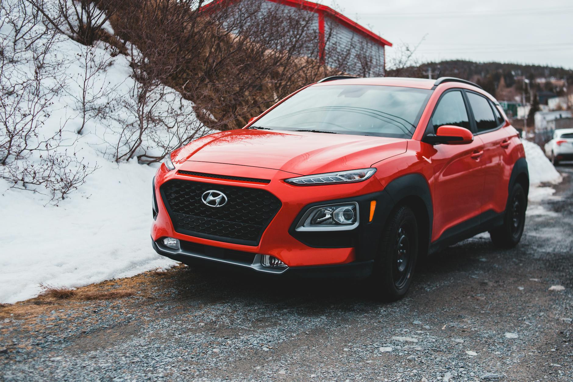 Czerwony SUV Hyundai zaparkowany na śniegu na tle zimowego pejzażu