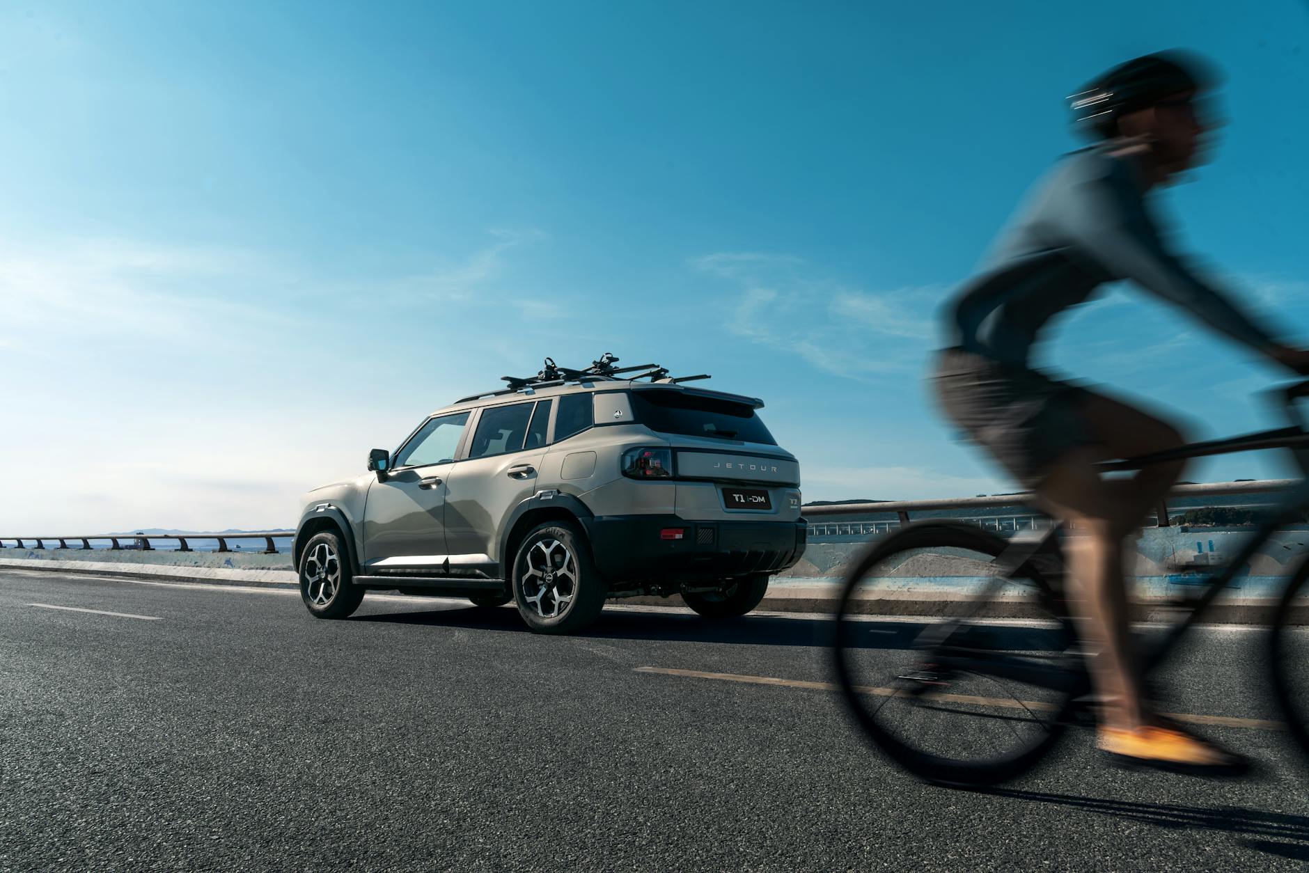 Hyundai Tucson z bagażnikiem na rower mijany przez rowerzystę na autostradzie