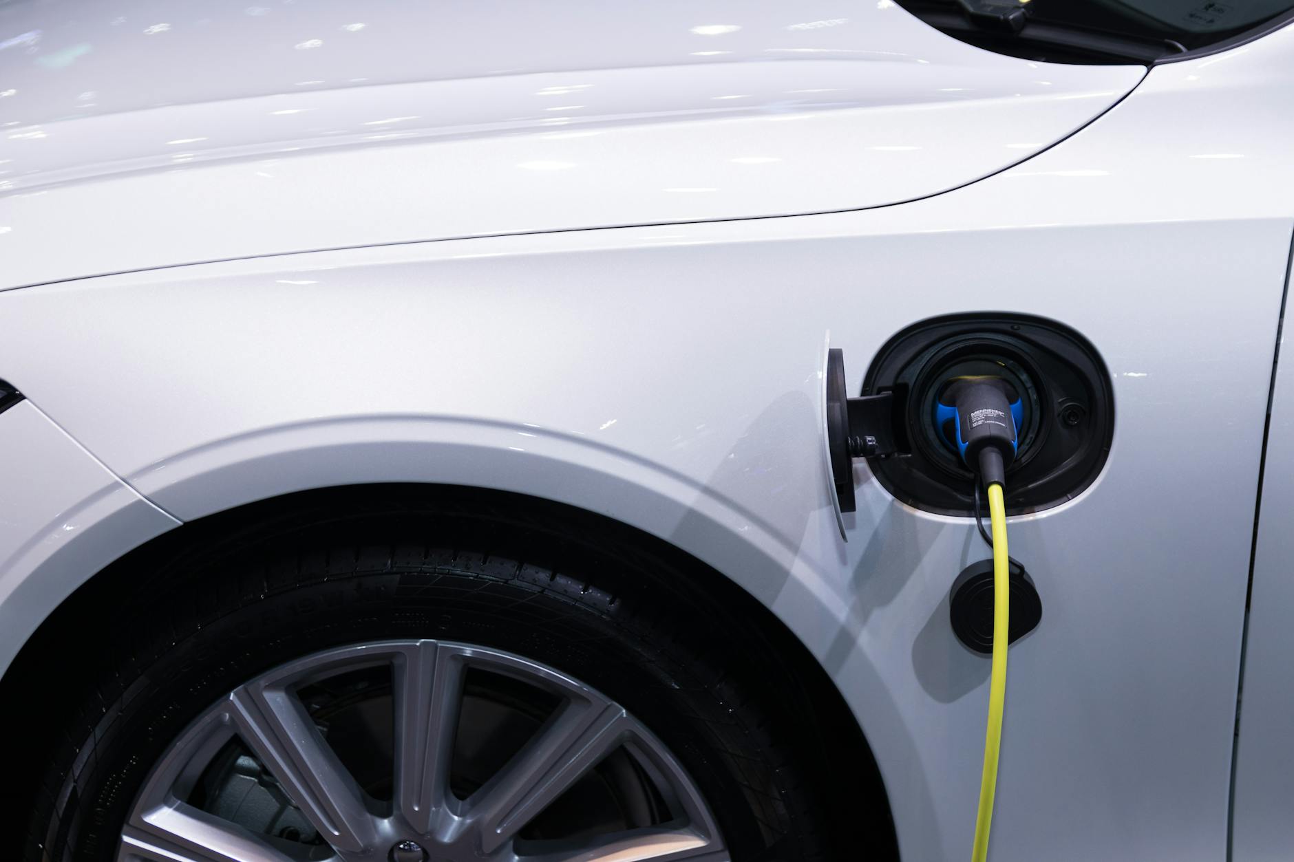 Biały elektryczny Mitsubishi Outlander podłączony do ładowania zbliżenie