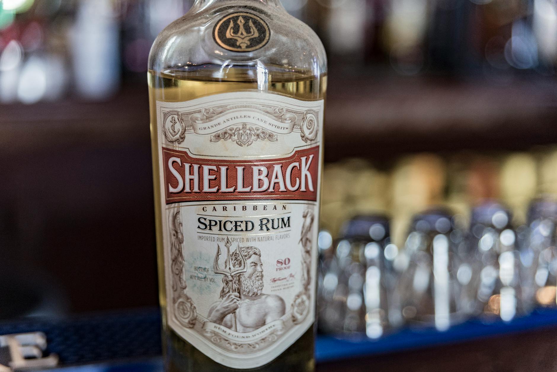 Butelka Shellback Caribbean Spiced Rum na tle rozmytego baru