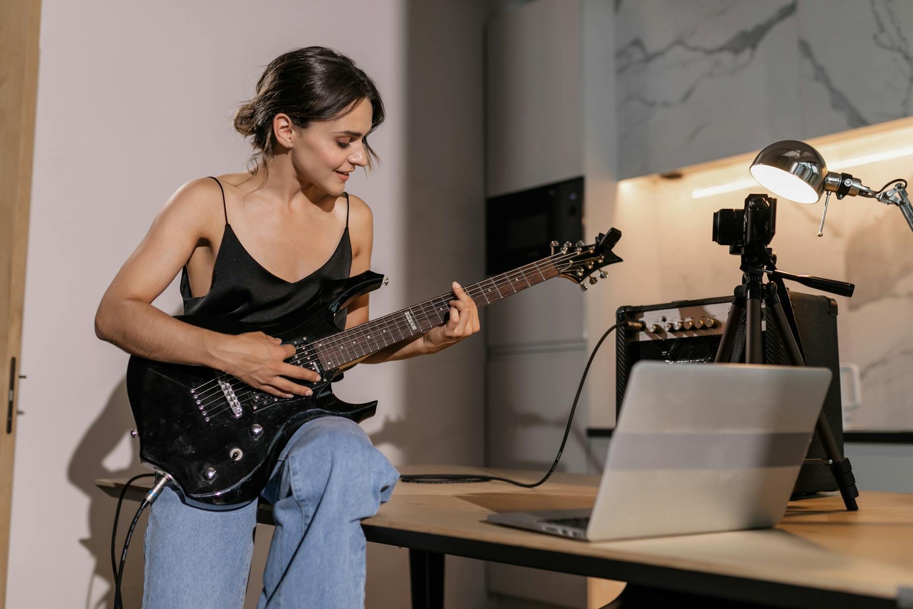 Kobieta nagrywa grę na gitarze elektrycznej w domowym studiu