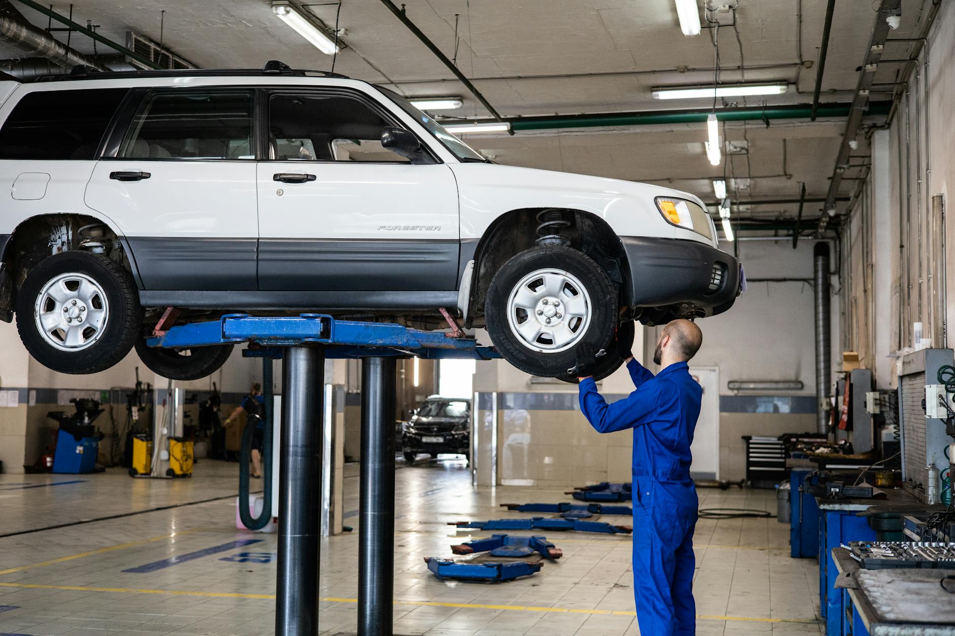 Mechanik ogląda białego Cadillaca CT6 na podnośniku w warsztacie