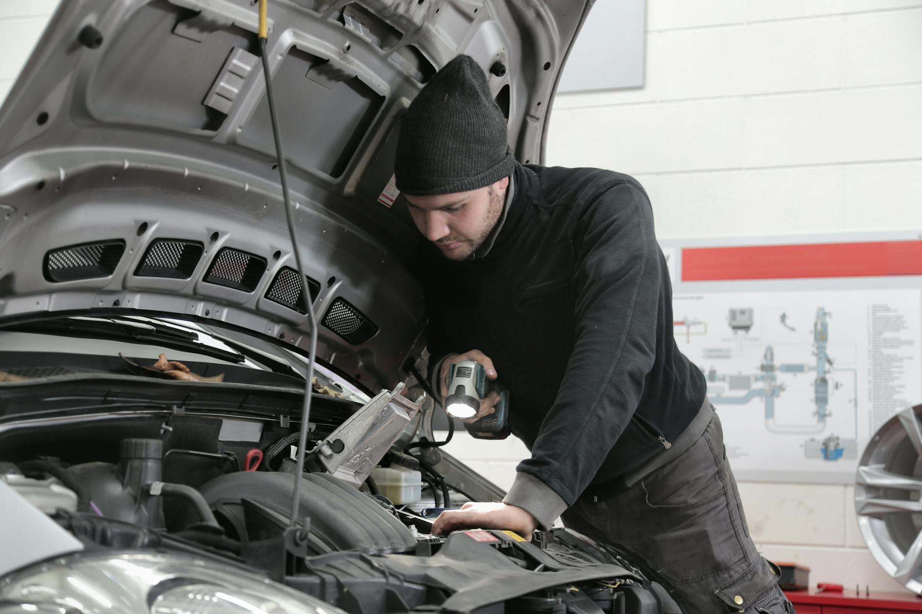 Mechanik z latarką dokładnie ogląda silnik Cadillaca w warsztacie