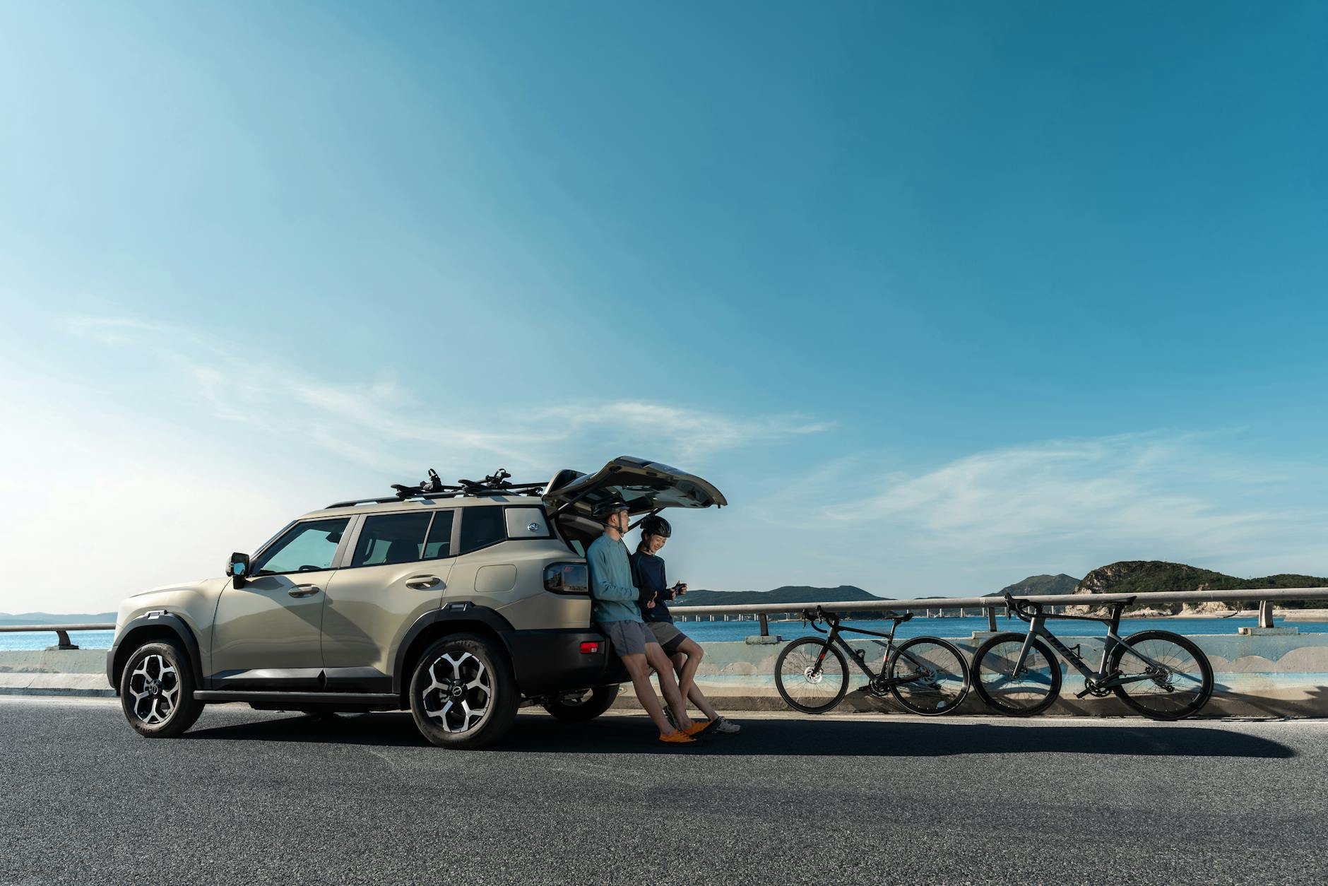 Mitsubishi Outlander PHEV z rowerami zaparkowany przy nadmorskiej drodze