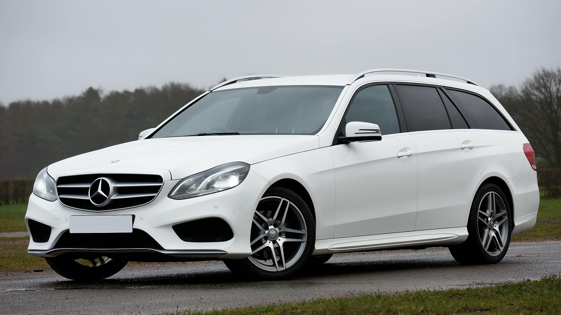 Białe kombi Mercedes E-Class zaparkowane na zewnątrz pod pochmurnym niebem