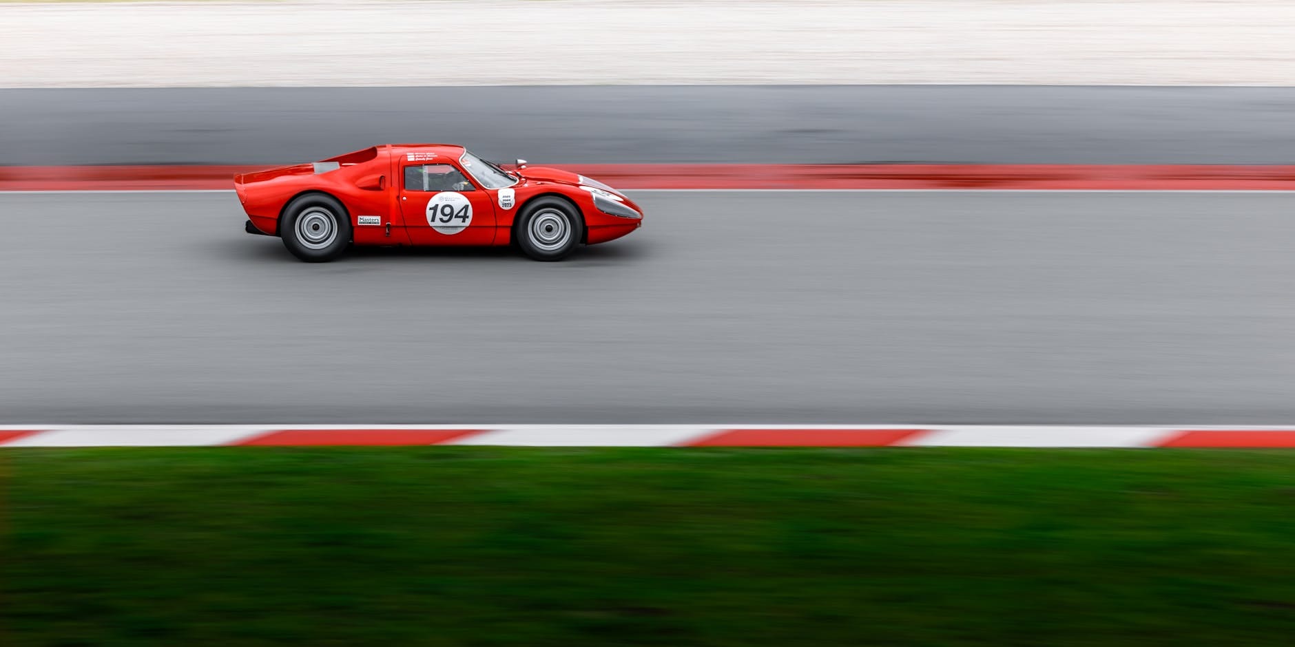 Czerwone wyścigowe Ferrari pędzące po torze, rozmyte tło ruchu