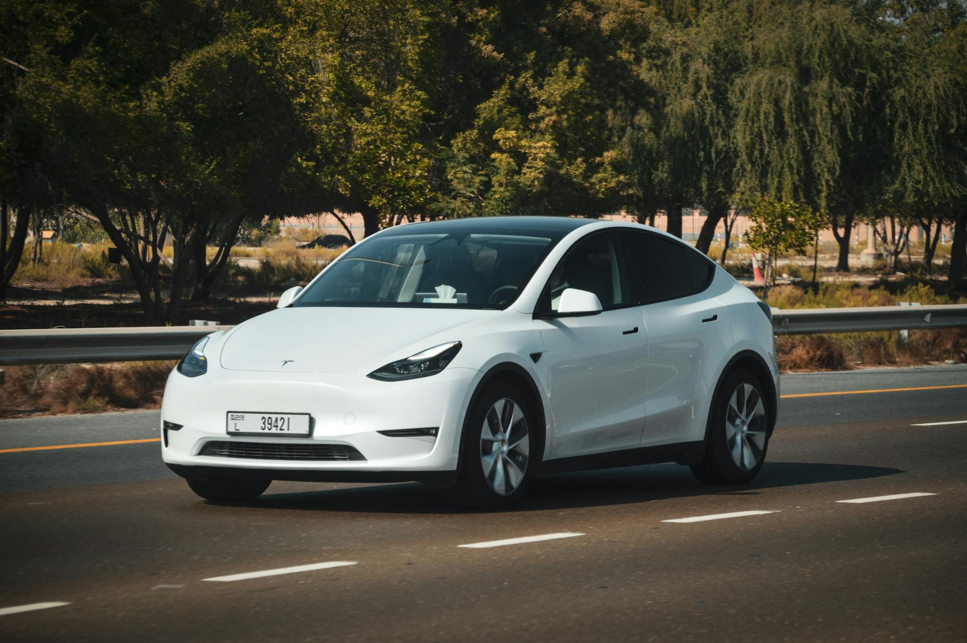 Biały elektryczny SUV jedzie autostradą w słońcu w Zjednoczonych Emiratach