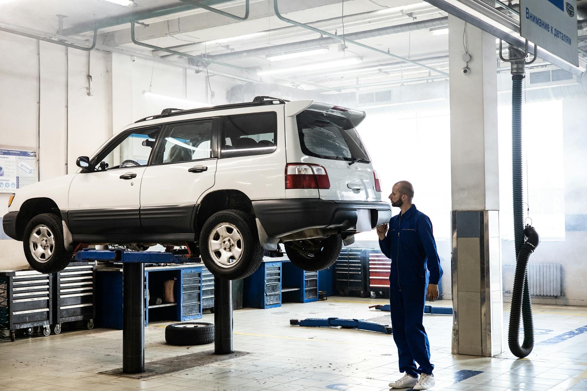 Mechanik sprawdzający podniesione SUV w nowoczesnym serwisie samochodowym