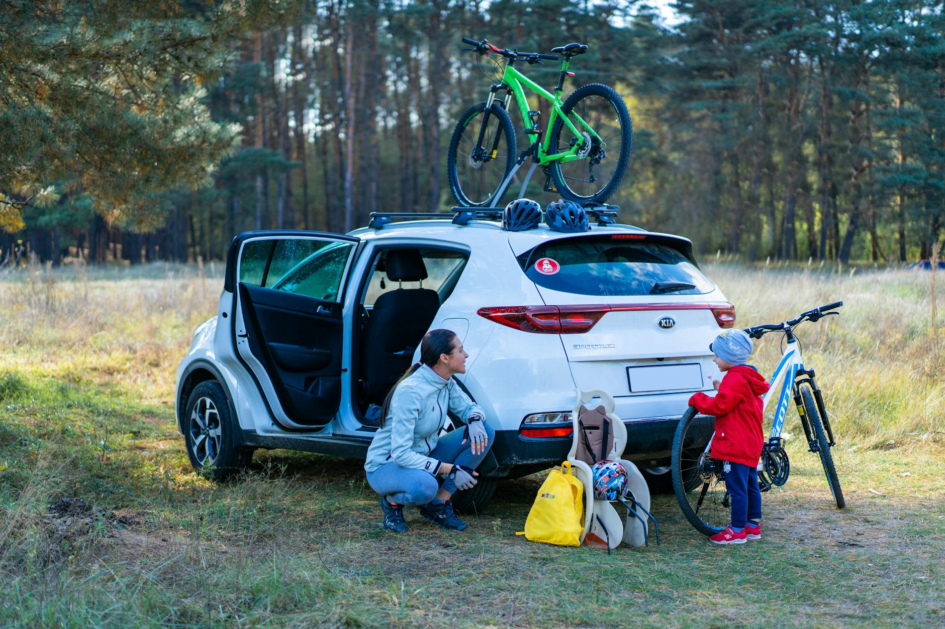 Mama z dzieckiem szykują rowery przy zaparkowanym Subaru w parku