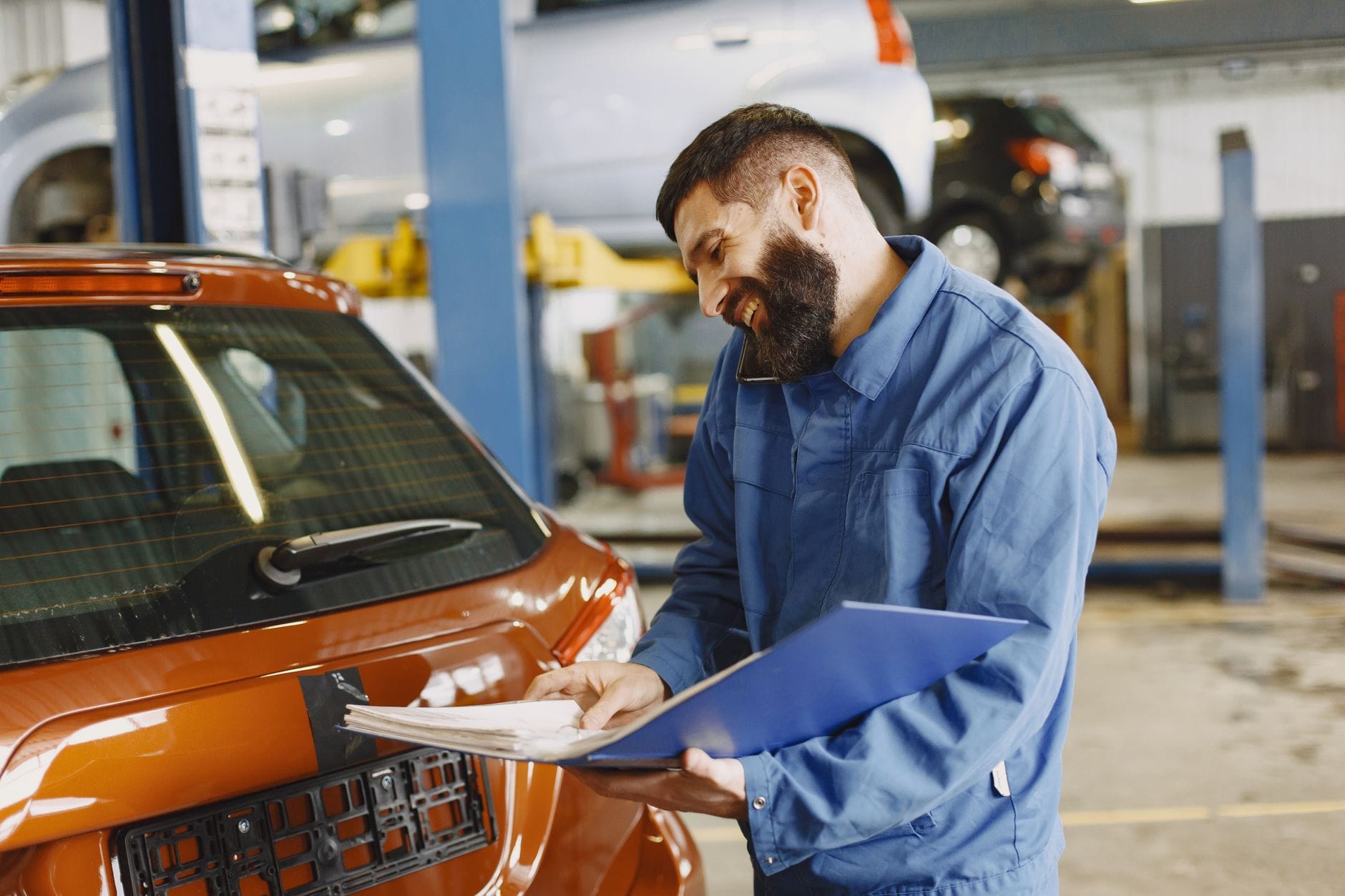 Mechanik BMW z dokumentami przy aucie w garażu serwisowym