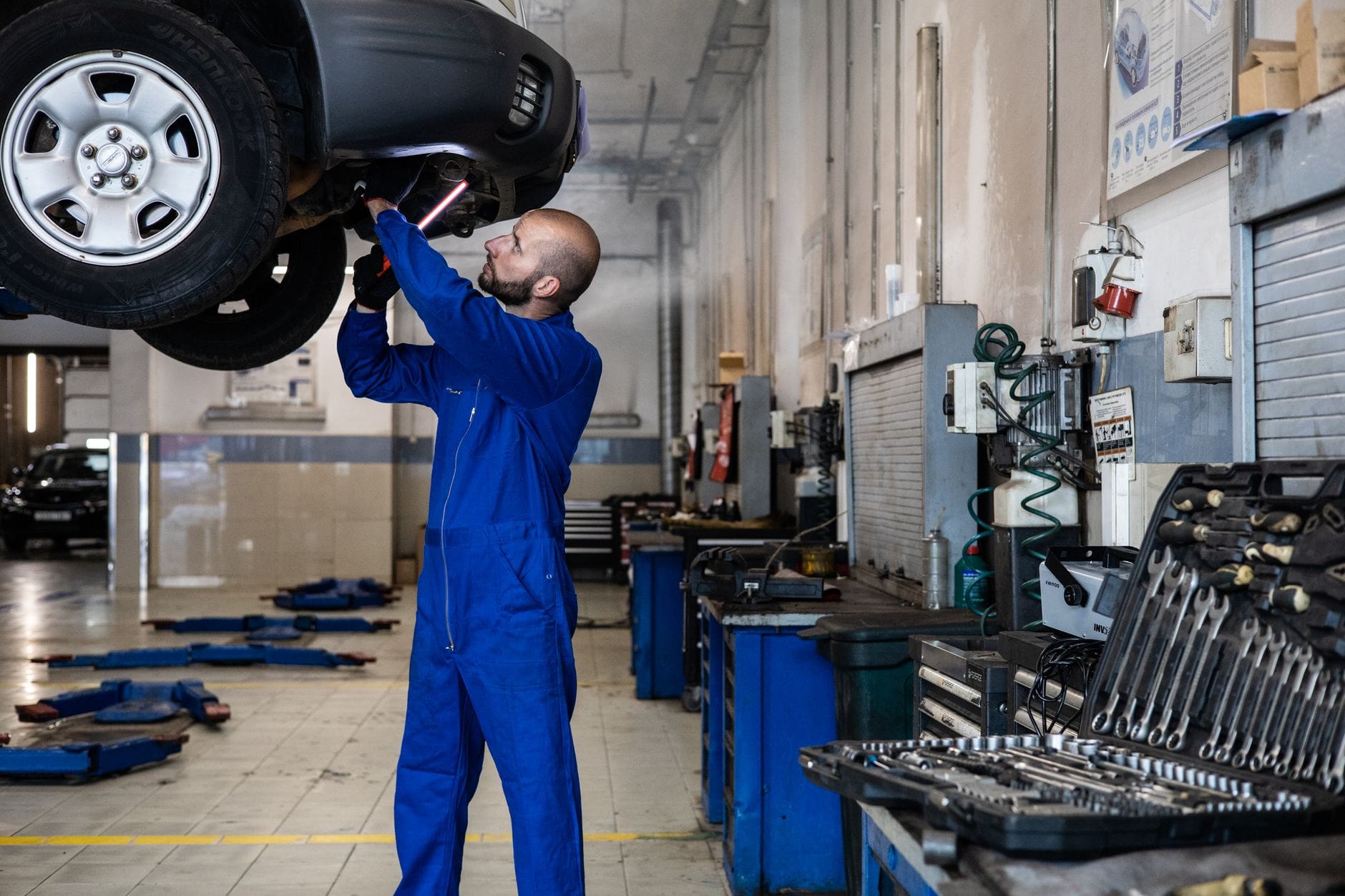 Mechanik sprawdza auto na podnośniku w warsztacie BMW Mechanik sprawdza auto na podnośniku w warsztacie BMW