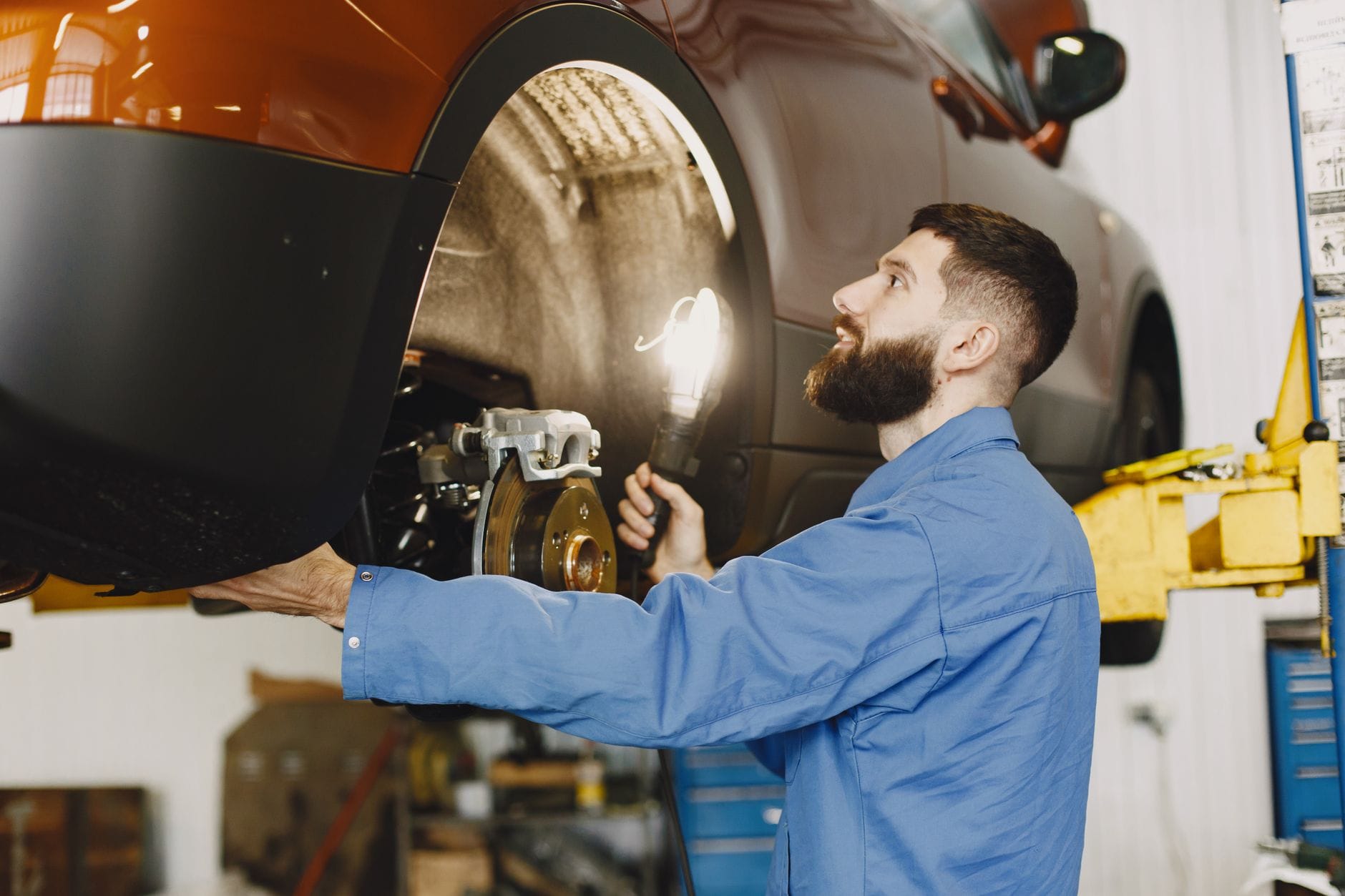Mechanik sprawdza hamulce BMW w dobrze oświetlonym warsztacie