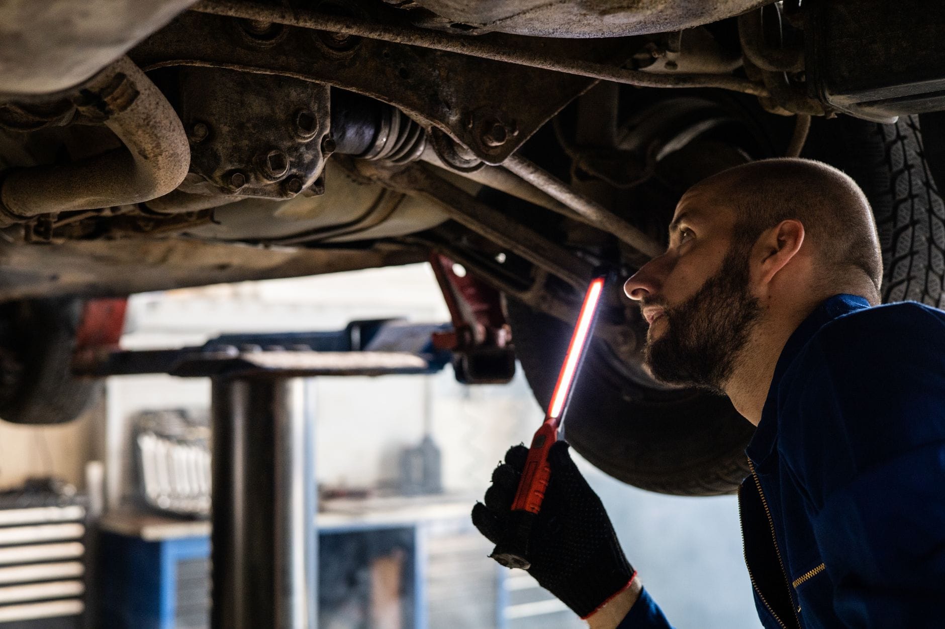 Mechanik sprawdza podwozie BMW latarką w warsztacie serwisowym